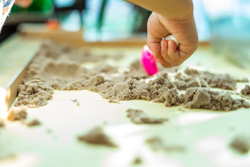 Child's hand playing with kinetic sand in preschool. The development of fine motor concept. Creativity Game concept.