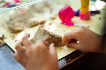 Obraz na płótnie Canvas Child's hand playing with kinetic sand in preschool. The development of fine motor concept. Creativity Game concept.