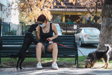 Young woman walking her dogs to exercise and relieve themselves during quarantine caused by the coronavirus pandemic