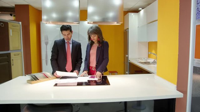 WS DS PAN Salesman and customer looking at plans and samples in kitchen showroom