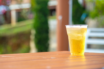 Beer in glass is placed on wooden table  in the resort.Beer in a plastic glass with bubble placed on the floor near the pool in the evening for a party.