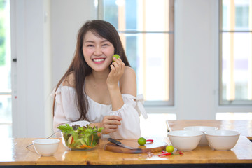 Obraz na płótnie Canvas Beautiful Asian women, beautiful smiles, good health, beautiful teeth, eating salad vegetable when working at home.