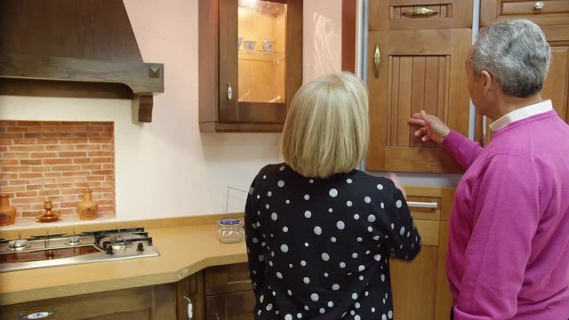 MS TS Mature couple examining furniture in kitchen showroom