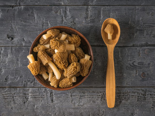 Fototapeta na wymiar A wooden spoon next to a bowl of morels.