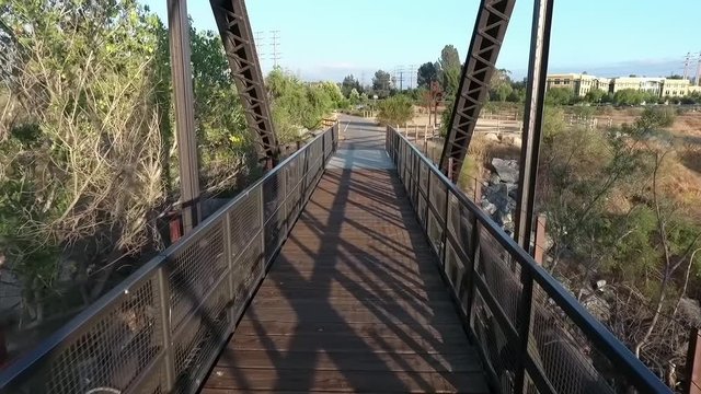 Aerial, low, drone shot through a small, steel bridge, in California