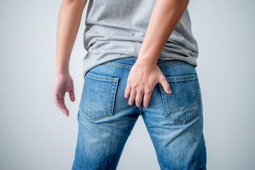 The young man touched his butt because of stomachache and hemorrhoids. .Concepts of health care and bowel problems
