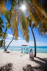 Colorful wedding arch gazebo pavilion made of bamboo and textile with fresh flowers decoration at sandy beach on sunny day for destination wedding ceremony in Dominican republic  