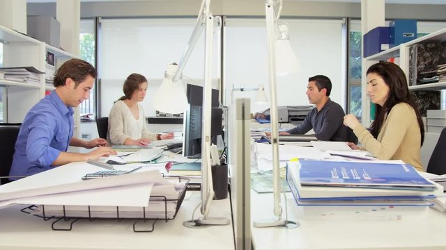 WS&nbsp;People working at desk in office, man comes up to woman to review documents