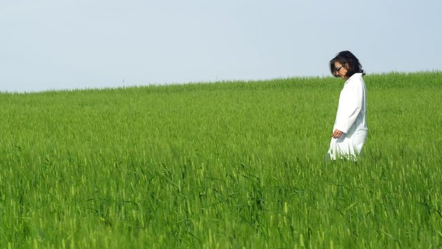 WS TS Woman in lab coat walking in wheat field, crouching and checking crops