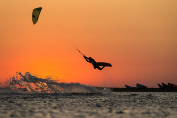 Professional kiter rides in the ocean against the background of incredible setting sun