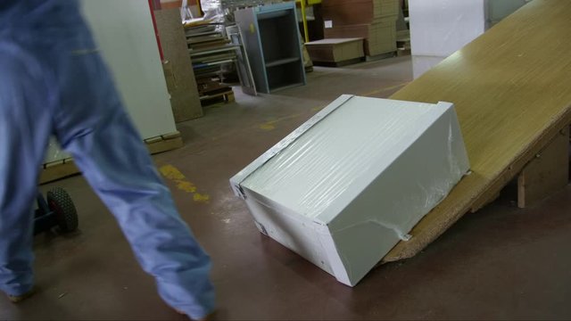WS TS MS Worker in furniture factory loading furniture onto cart