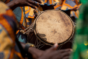 A closeup photo shows a drum and  hands at the kente festival in Ghana, West Africa.