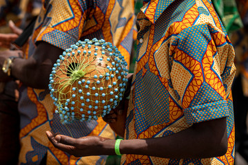 A closeup photo shows a drummer playing an African Shekere gourd percussion instrument while...