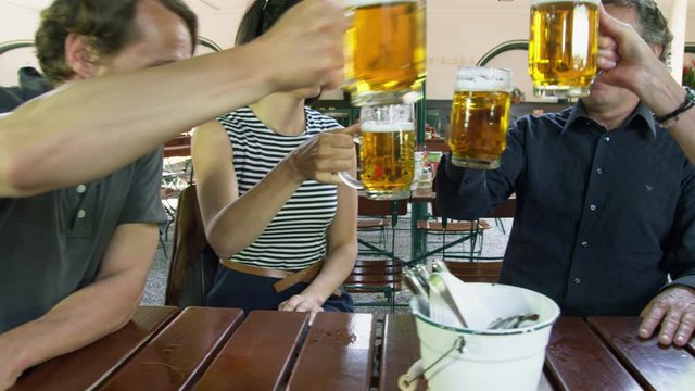 MS DS Two couples sitting at table in beer garden and making celebratory toast