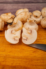 Halves of cut mushrooms and young mushrooms scattered on a wooden background. Close up.