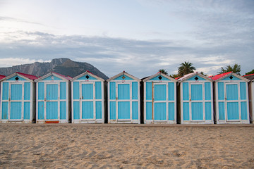 Little blue houses on the beach. A place to store beach utensils. Rasset (sunset) on the Mediterranean coast. The concept of a relaxing beach holiday. Old cracked paint