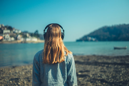 Young woman with headphones by the sea in small town