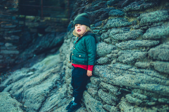 Preschooler boy relaxing by rocks outdoors in spring