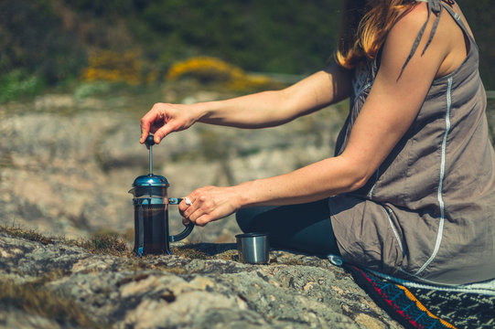Young woman making coffee in nature with a french press