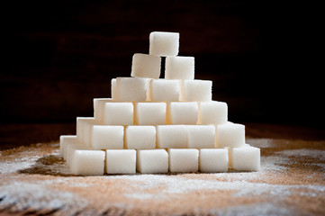 A pyramid made of refined sugar cubes, standing on a dark wooden surface.