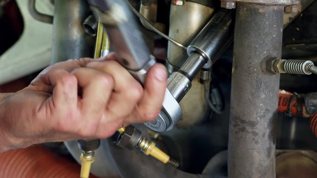CU Hand of mechanic tightening bolt with ratchet wrench