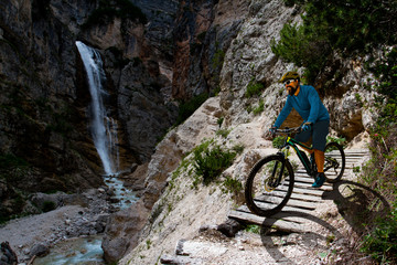 Man cycling on electric bike, rides mountain trail. Man riding on bike in Dolomites mountains...