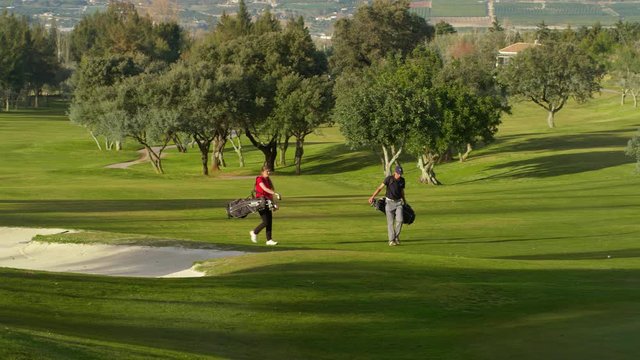 WS&nbsp;TS Young man and woman playing golf on fairway, man taking shot