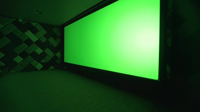 Modern cinema, view of the big green screen in the cinema hall, chromakey template in empty cinema hall.