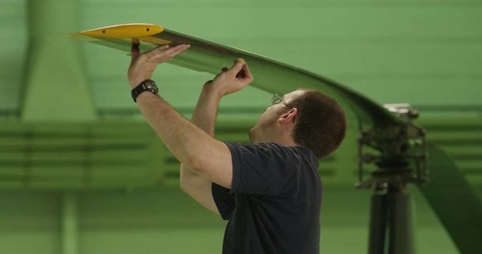 MS Aviation mechanic performing tapping inspection of helicopter rotor blade
