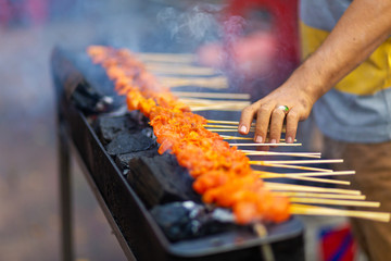 Street food seller in Asia fries chicken mini barbecue on the grill