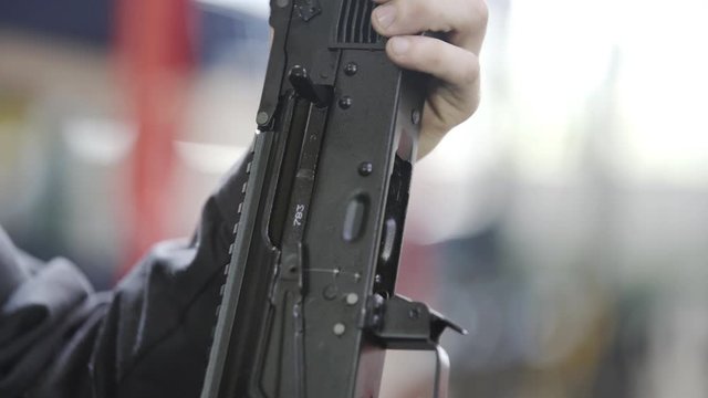 Factory assembly of a Kalashnikov assault rifle. Close up of charging rifle. AK47 loading. Factory worker hand charging machine gun. Factory worker collects the AK-47.