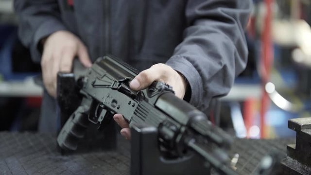Factory assembly of a Kalashnikov assault rifle. Close up of charging rifle. AK47 loading. Factory worker hand charging machine gun. Factory worker collects the AK-47.