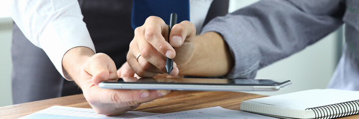 Close-up of worker and client discussing condition of contact. Customer reading and signing electronic agreement in office. Business company and negotiations concept