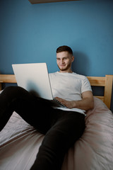 guy using laptop on a bed