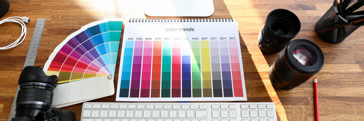 Color calendar book with color trends sign on designer wooden table closeup background. Color proof device concept