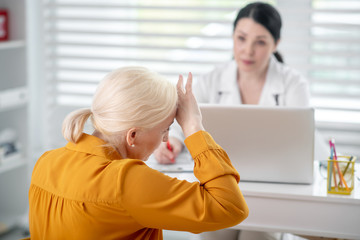 Woman in white coat looking at patient in yellow.