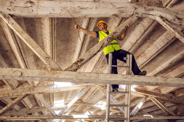 Construction site builder climbing on ladder and preparing to fix rooftop.