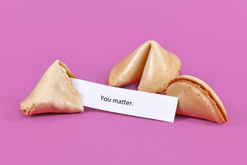 Open fortune cookie with motivational text on paper saying 'You matter' on violet background