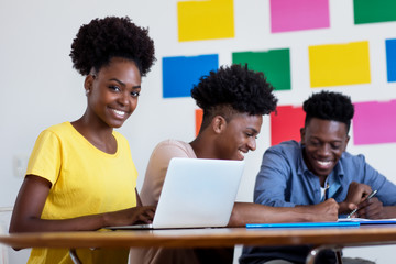 Learning african american female student at computer with group of students