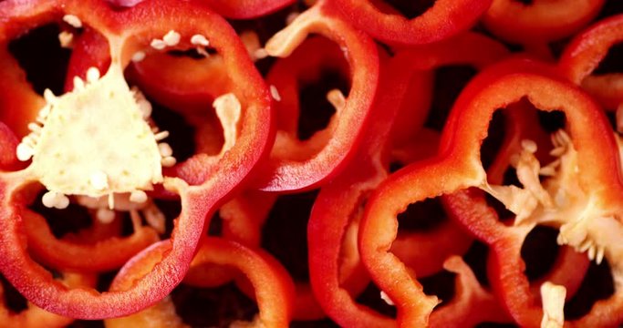 Slices of ripe sweet red pepper rotating slowly.