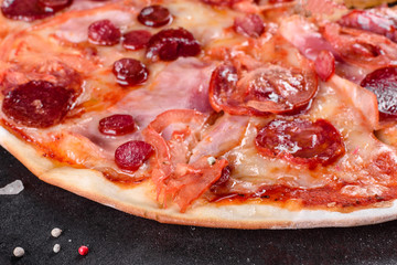 Pepperoni pizza with mozzarella cheese, salami, tomatoes, pepper and spices