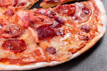 Pepperoni pizza with mozzarella cheese, salami, tomatoes, pepper and spices