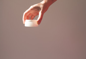 Skin care packaging in female hand.Beauty product for face skin,plant shadow white background. Scincare cosmetic concept