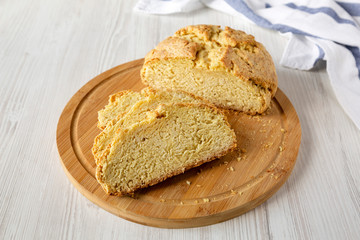 Homemade Irish Soda Bread on a bamboo board on a white wooden table, side view. Close-up.