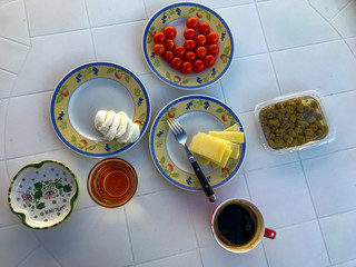 Italian tourist breakfast. Tomatoes, cheese, olives and coffee on a white table.