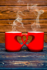 two heart shaped mugs with tea on brown background

