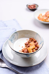 Healthy breakfast yogurt bowl with granola and caramelized bananas and nuts on grey concrete background. Selective focus
