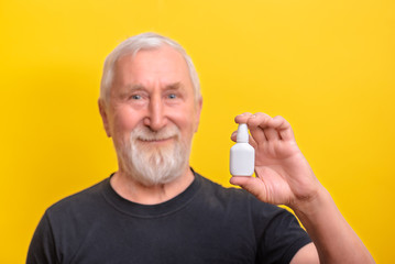 Senior man is holding nasal spray copy space and mock up. sarcasm emotion