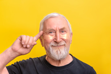 Senior man with eye patch gold and snail showed to it copy space