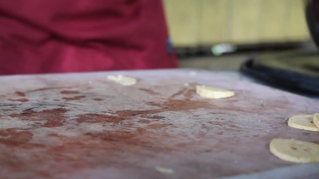 slicing delicious banana in a rustic way in slices on a cutting board to make fried plantains. 
cooking bananas